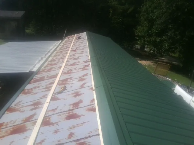 Old rusted panels beside newly installed green metal roofing — Wind Damage Roof Repair by Roofing Brothers in Danvers