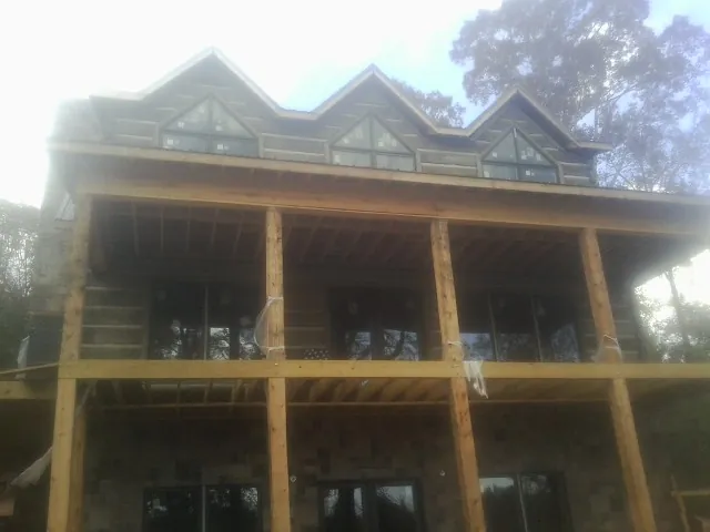 Dormers and porch framing on a large log home under construction — Roof Coating work by our crew in Danvers