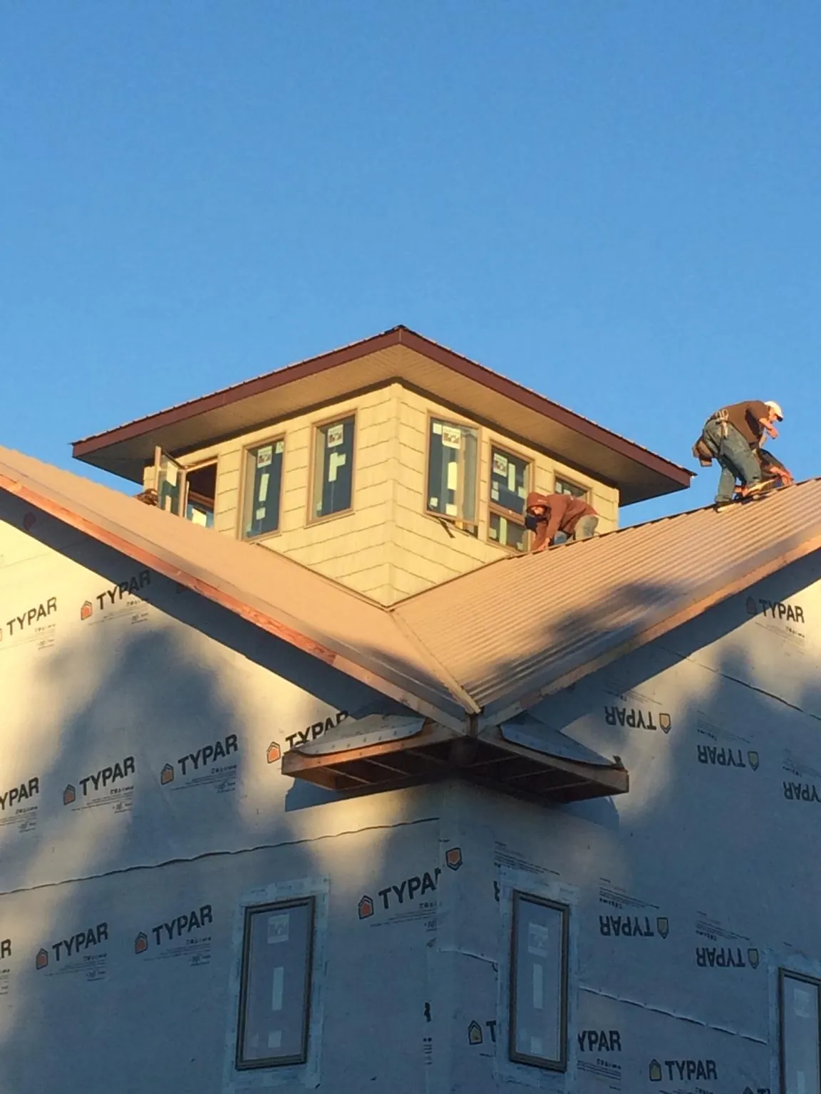 Roofers working around a rooftop cupola on a new metal roof at sunset — Roof Waterproofing in Danvers by Roofing Brothers